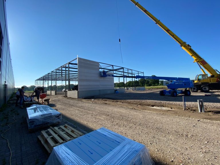 Staalconstructie van de tweede nieuwbouwhal naast het hoofdpand in Veldhoven, met een kraan en hoogwerker